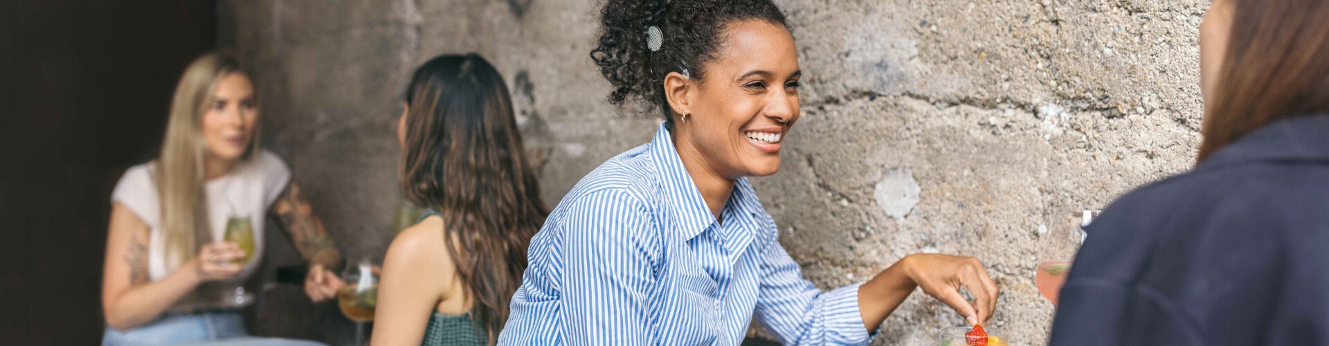 Cochlear Implants SONNET 3 woman smiling and having a conversation while using SONNET 3 at a noisy café